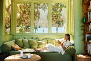 Young woman text messaging on her phone while relaxing on a sofa in her sunny living room at home